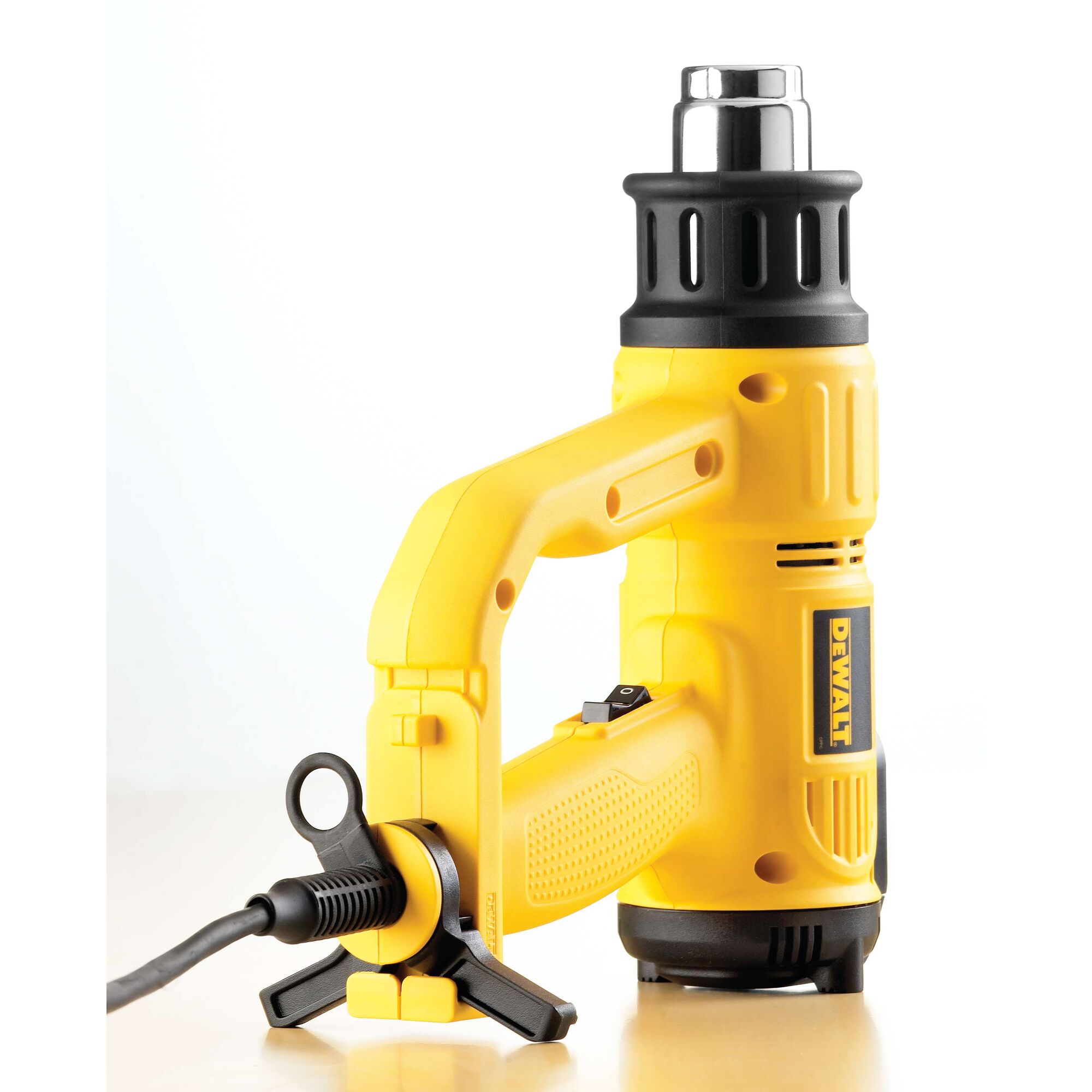 A yellow and black DEWALT heat gun with a power cord and ergonomic handle, placed on a light surface.