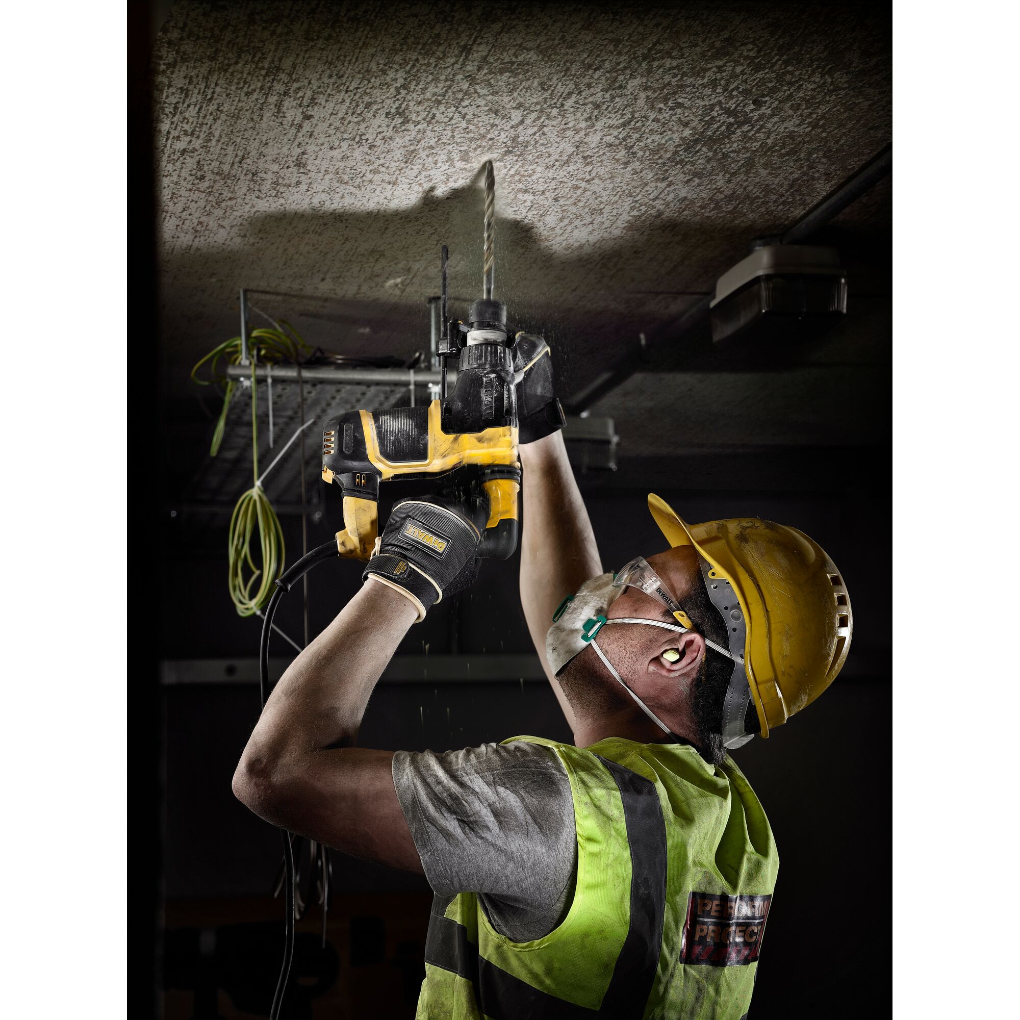 Worker uses DEWALT drill bits DT9580, DT9580-QZ for ceiling work; safety gear worn. Photography product.