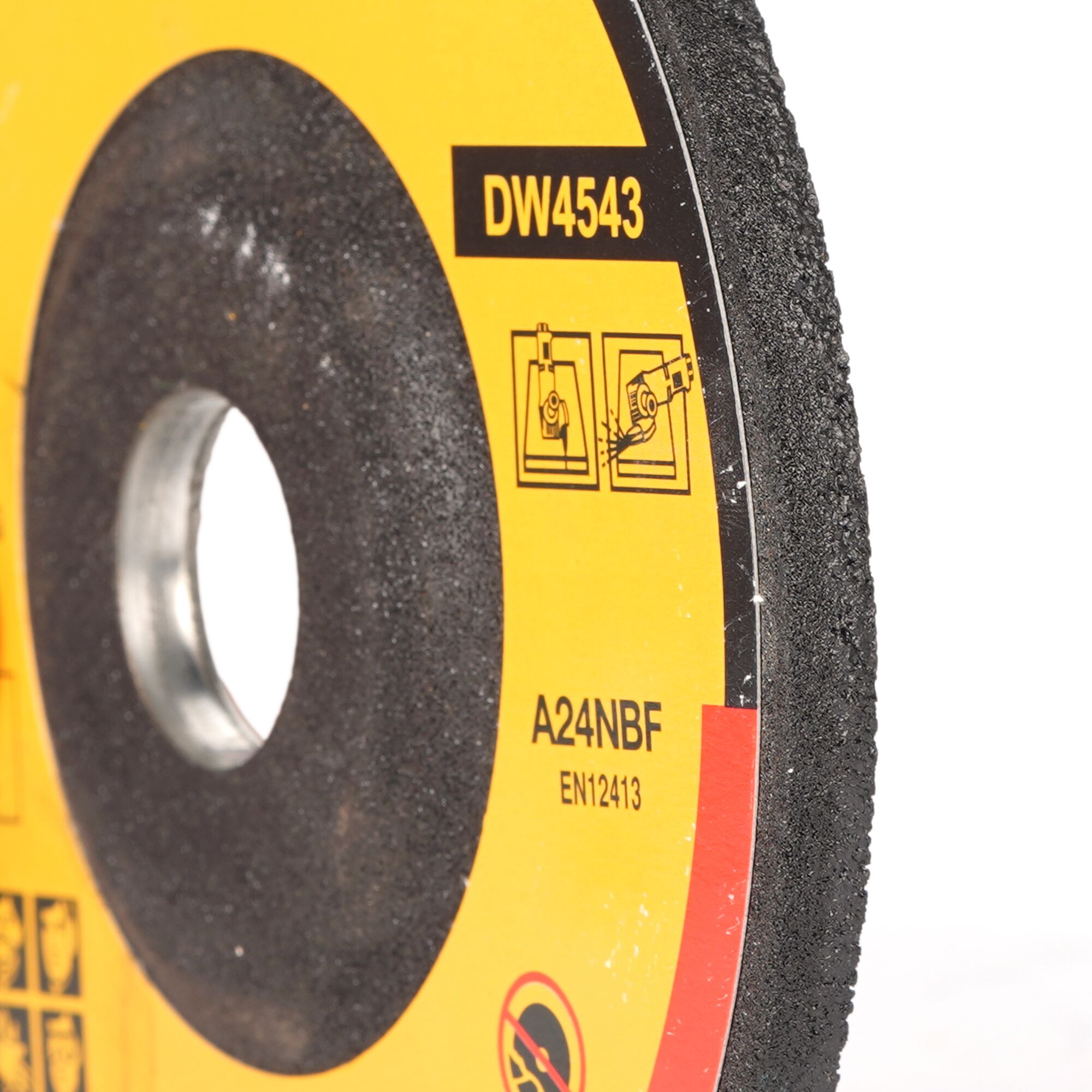 Close-up of a DEWALT DW4543 abrasive cutting disc, mainly black with a yellow label showing usage and safety icons, as well as the model number and technical specifications.