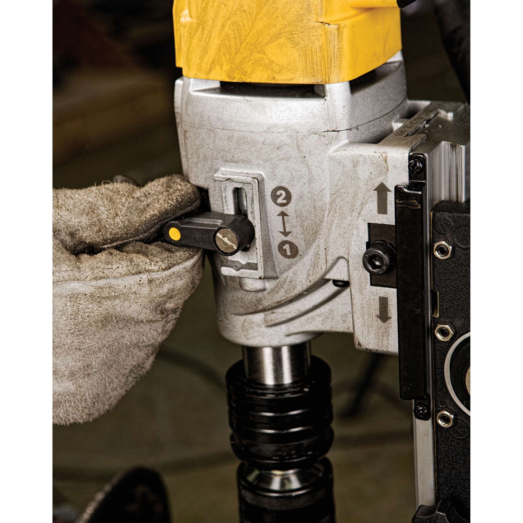 Close-up of a gloved hand operating a control lever on a DEWALT DWE1622K magnetic drill press.